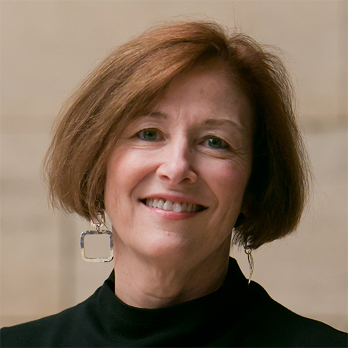 White woman with short brown hair smiling and wearing a black shirt